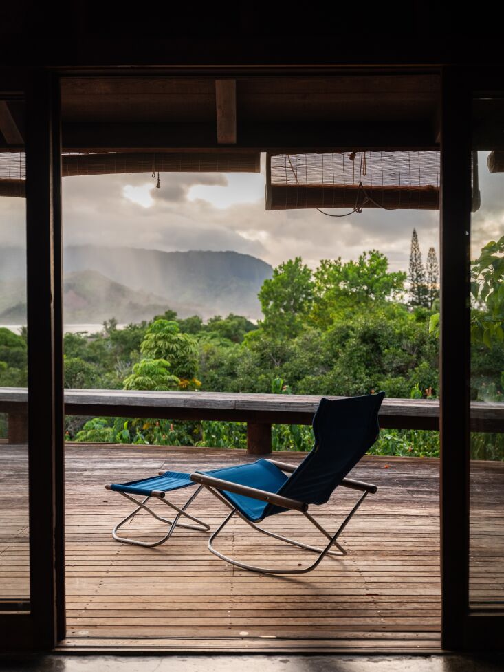 On the deck, overlooking an ocean of green (and the real ocean), a Nychair X-Rocking Chair by Takeshi Nii, reupholstered with Sunbrella fabric, makes a strong statement. Photograph by Kate Berry courtesy of Beatrice Faverjon, from Hawaiian Modernism: A \1970s Redwood House on Kauai, Preserved and Refinished by Beatrice Faverjon.