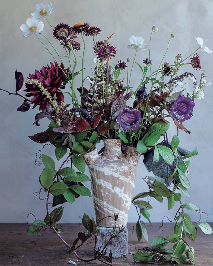 Palmer grows a range of flowering climbers and vines, not only for the colors and texture they bring in the garden but also for their distinct character in arrangements like this arrangement in which cup and saucer vines trail out of a marbleized, three-spouted vase Palmer designed.