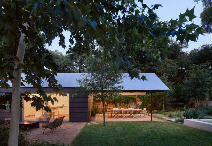 “The aim was for it to be as simple as possible, not over-designed,” says Grabiel of the new covered patio. The couple planted many native trees, including desert willows, cedar elms, and four live oaks, including the one centered in the lawn. The lawn is subtly graded to convey the water away from the house, which sits on grade.