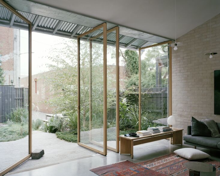 Floor-to-ceiling pivot doors help blur the line between outdoors and indoors in this new build by Lovell Burton. Photograph by Rory Gardiner, courtesy of Lovell Burton, from An Architect Couple’s New Extension Welcomes All.