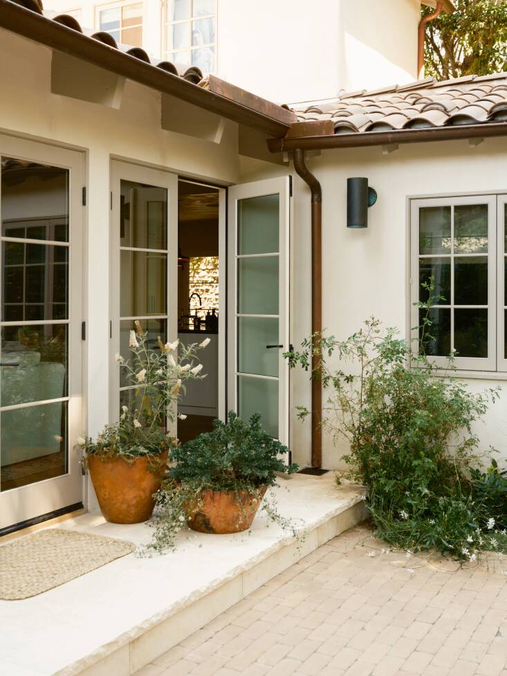 French doors, offset by ORCA-designed copper planters, open out from the living room to the back patio.