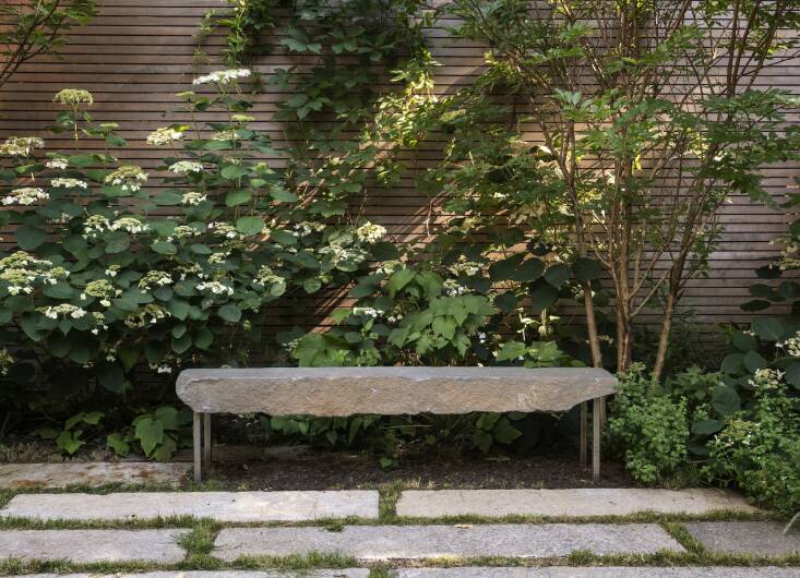  Above: The bench, flanked by two crepe myrtles, is a chunk of bluestone Farris found at the stone yard and commissioned 6\18 Design to make it look like it\2\17;s floating. Farris says the design of the clear cedar fence (a sustainable wood) was inspired by a project by Tom Stuart Smith.