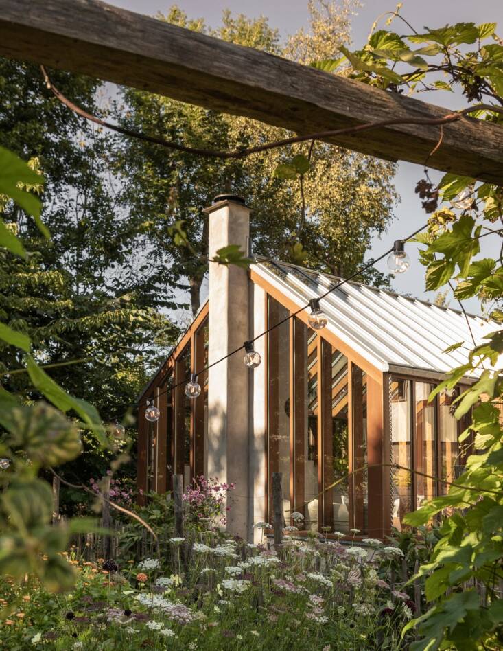 The orangery is surrounded by wildflowers and trees.