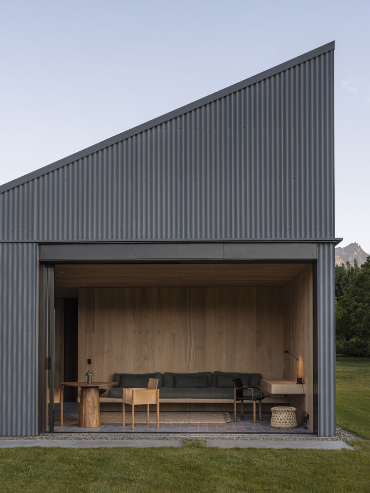 We love how this room opens up completely to the outdoors. Equally impressive: the hardscaping. Notice how the floor transitions from limestone tile to pebble to concrete, with a square of grass serving as a path. To see the rest of this extraordinary project, check out Orchard House: A Flexible Family Compound in New Zealand, by Fearon Hay and Katie Lockhart. Photograph by David Straight for Katie Lockhart Studio. 