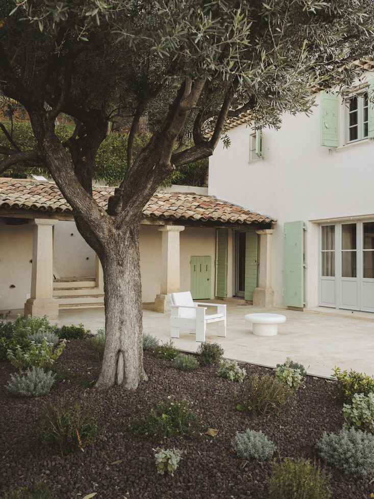 A Rietveld design, the Craft Lounge Chair in White, sits with an Addaia Cement Coffee Table from Kave Home in this dreamy French courtyard. Photograph by Jean-Baptiste Thiriet for Pareil, from A Provençal Bastide in Tourtour, France, Restored by Pareil Architecture.