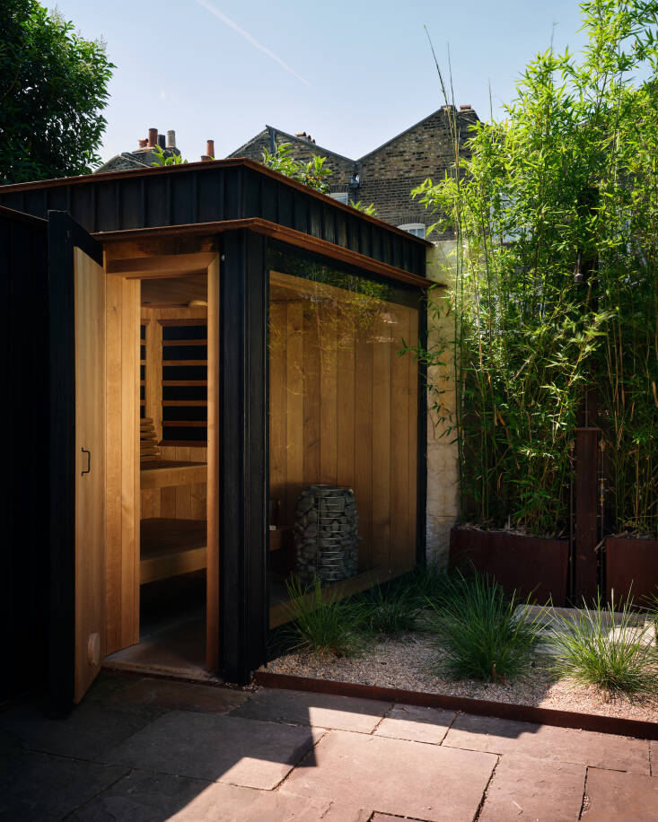 On the exterior of the sauna and changing rooms, quarry riven limestone and charred timber come together for \2\20;a very tactile quality similar to the main extension,\2\2\1; Nathaniel says. \2\20;The limestone in particular has a very raised grain which gives an enjoyable, monumental quality to what is really a tiny building.\2\2\1; Beside it, Sophie placed tall golden bamboo (Phyllostachys aurea) in bespoke corten planters, forming a dense green screen to obscure the outdoor shower nestled inside it.
